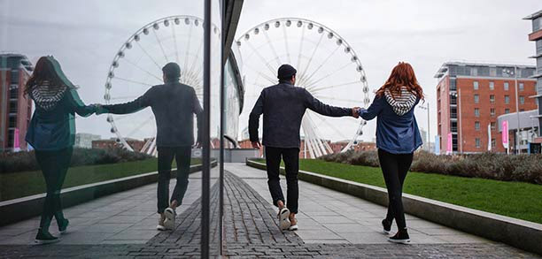 A couple walking towards a ferris wheel.